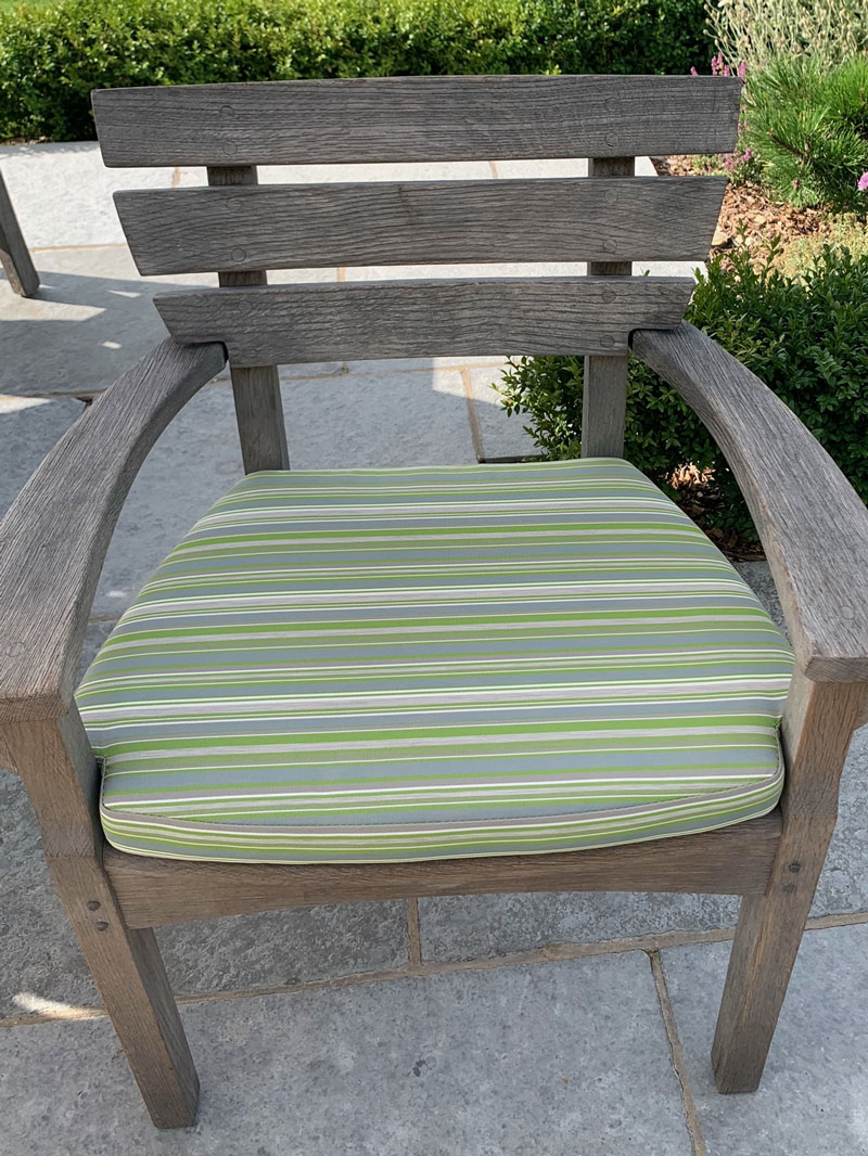 A shaped replacement outdoor cushion for a wooden armchair.